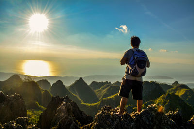 Rear view of man standing on mountain against sky