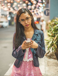 Portrait of young woman wearing sunglasses on street