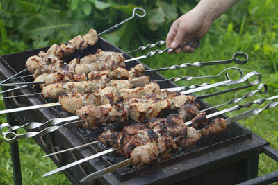 Cropped image of person preparing meat on barbecue grill