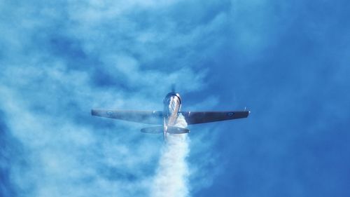 Low angle view of aircraft in flight against clouds