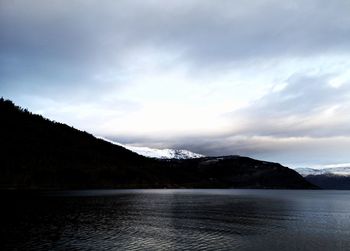 Scenic view of lake by mountains against sky