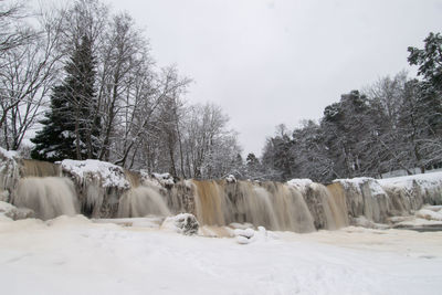 Scenic view of snow covered icy waterfall against sky