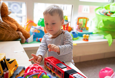 Toddler boy plays with car toys in the children's room. educational toys for young children. 