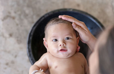 Happy smiling baby newborn taking a bath and looking at camera with beautiful brown eyes. 