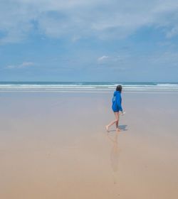 Full length of woman walking at beach against sky