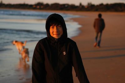 Portrait of young man wearing hooded shirt at beach