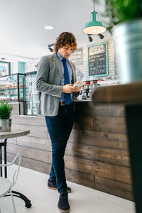 Businessman using phone while standing in cafe