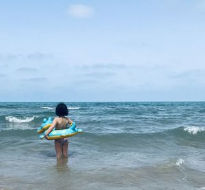 Rear view of man on beach against sky