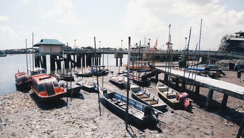 Boats moored at harbor against sky