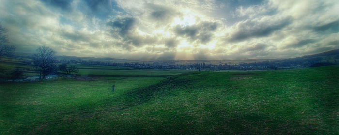 Scenic view of grassy field against cloudy sky