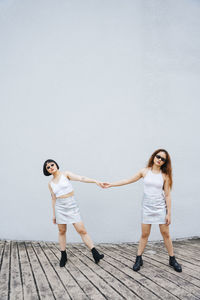 Full length of a young woman standing against the wall