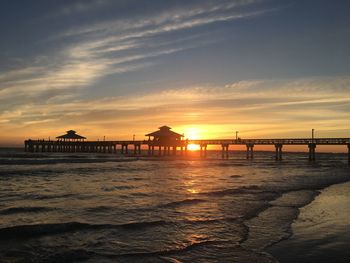 Pier on beach during sunset