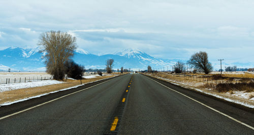Empty road leading towards mountains during winter