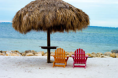 Lounge chairs on beach against sky