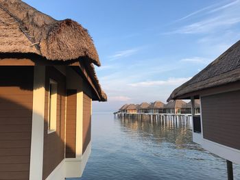 Stilt houses over sea against sky