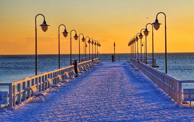 Pier over sea against sky during sunset