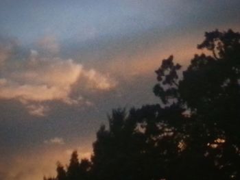 Low angle view of silhouette trees against dramatic sky