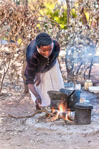 Woman preparing food on campfire outdoors