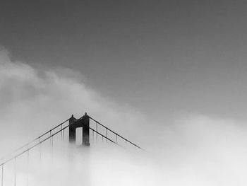 Low angle view of suspension bridge against cloudy sky, san francisco ca.