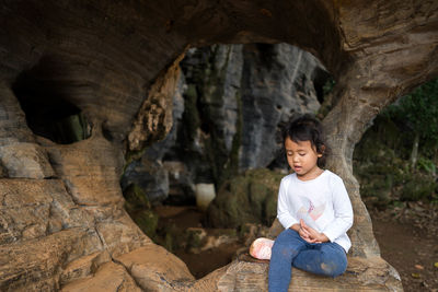 Full length of little girl sitting on rock