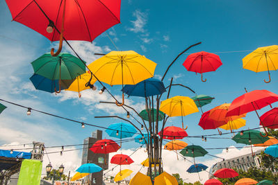 Low angle view of multi colored umbrellas hanging against sky