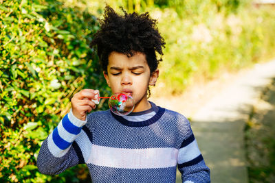 Cute boy blowing bubble on footpath