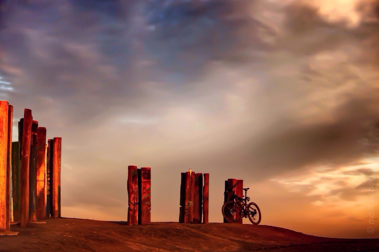 bicycle, sky, cloud - sky, cloudy, land vehicle, transportation, sunset, mode of transport, cloud, parking, built structure, stationary, outdoors, weather, silhouette, overcast, architecture, parked, riding