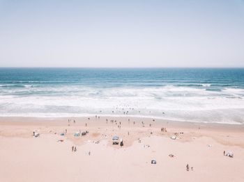 Group of people on beach against clear sky