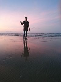 Full length of man standing at beach during sunset