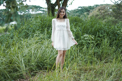 Portrait of young woman standing amidst plants on land