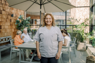 Portrait of smiling female nurse standing at nursing home