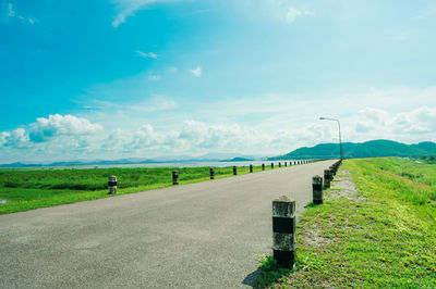 Road amidst field against sky