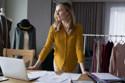 Fashion designer standing at desk in workshop