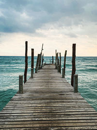 Wooden jetty on pier over sea against sky