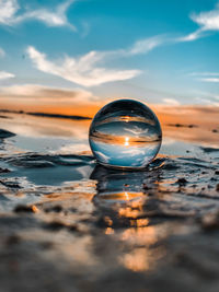 Close-up of crystal ball in sea against sky