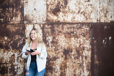 Portrait of a smiling young woman standing on wall