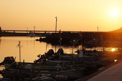 Boats moored at harbor against sky during sunset