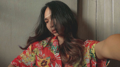 Portrait of young woman looking away against wall