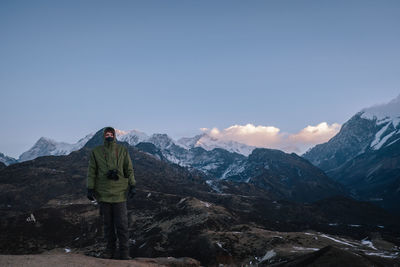 Rear view of man standing on mountain against sky