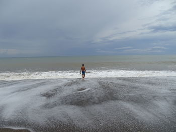 Rear view of man on beach against sky