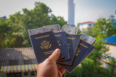 Cropped hand holding passports and paper currency in city