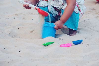 Low section of girl playing on sand at beach