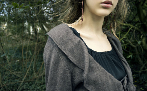 Midsection of woman standing against plants