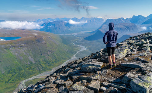 Rear view of man walking on mountain against sky