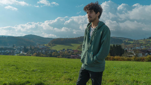 Young man standing on field against sky