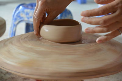 Cropped hands of person making pot in workshop