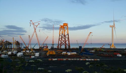 Cranes at harbor against sky