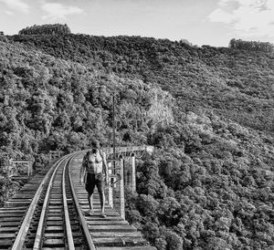 Full length of young man walking on railway bridge against mountain