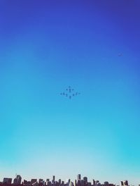 Low angle view of airplane flying against clear blue sky