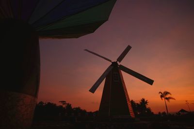 Low angle view of traditional windmill against sky during sunset